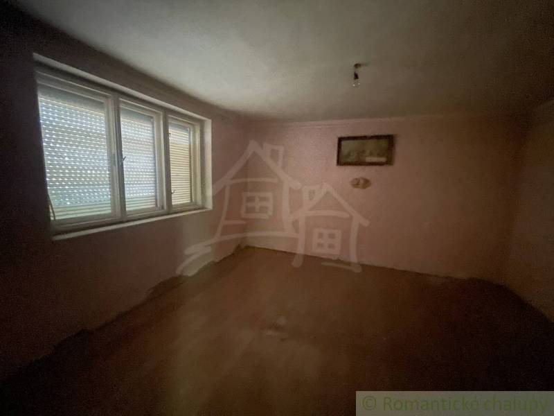 Prázdný pokoj v rodinném domě s podlahou s dřevěným dekorem a velkým oknem.