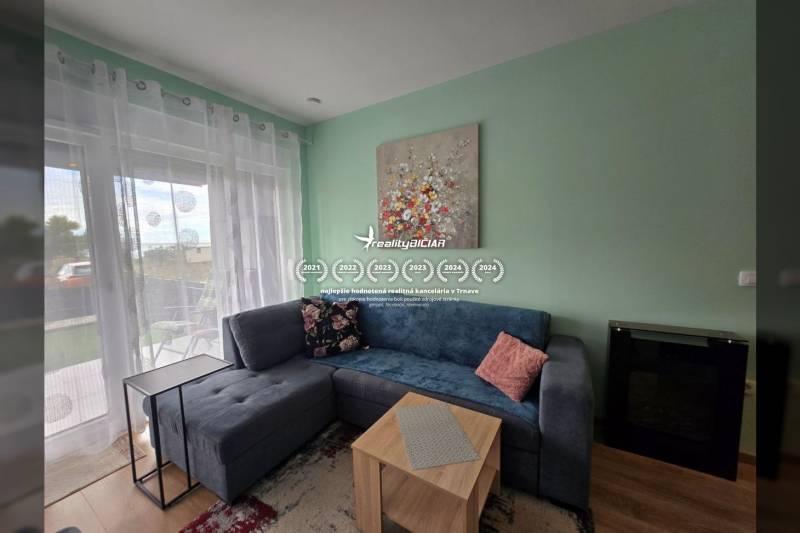 Obývací pokoj rekreačního apartmánu s pohovkou, stolkem, dekoracemi a oknem s výhledem.