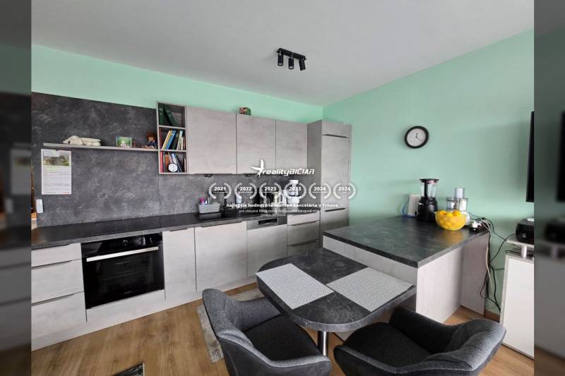 Kuchyně s jídelním stolem a podlahou s dřevěným dekorem v Rekreačním apartmánu.