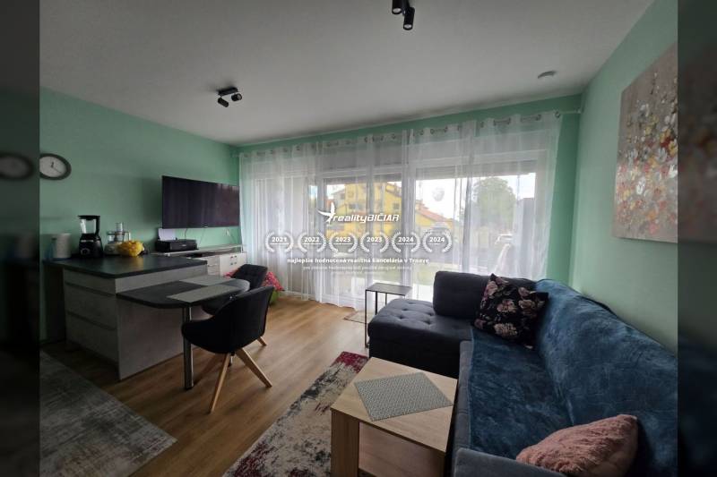 Obývací pokoj v rekreačním apartmánu s podlahou s dřevěným dekorem, pohovkou a TV.