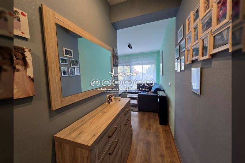 Hala v rekreačním apartmánu s podlahou s dřevěným dekorem a zrcadlem na stěně.