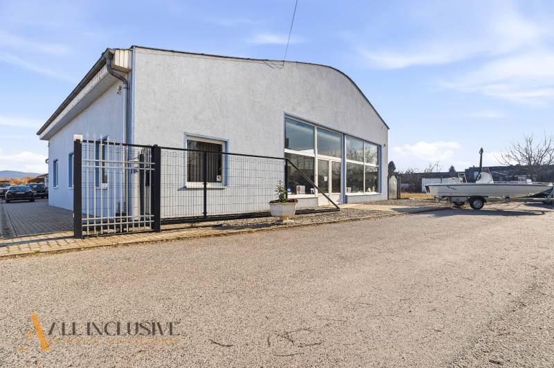 Obchodní prostory v Štúrově s šedou fasádou, parkováním a přístřeškem.