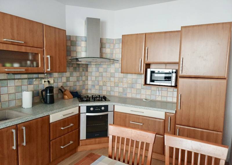 Kuchyně v 3-pokojovém bytě s dřevěnou kuchyňskou linkou a kachličkovým obkladem.