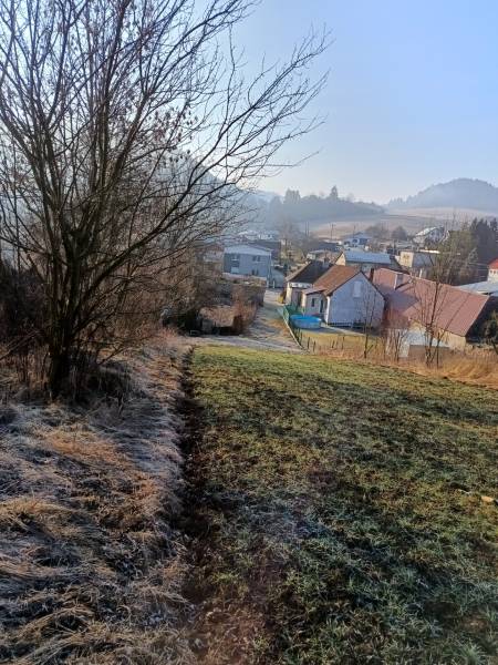 Krajina ve Sklabini s pozemky na bydlení, domy a stromy v pozadí.