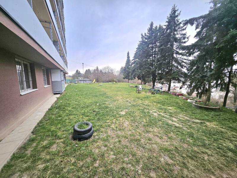 Exteriér 3-pokojového bytu v Bánovcích nad Bebravou s trávníkem a stromy.