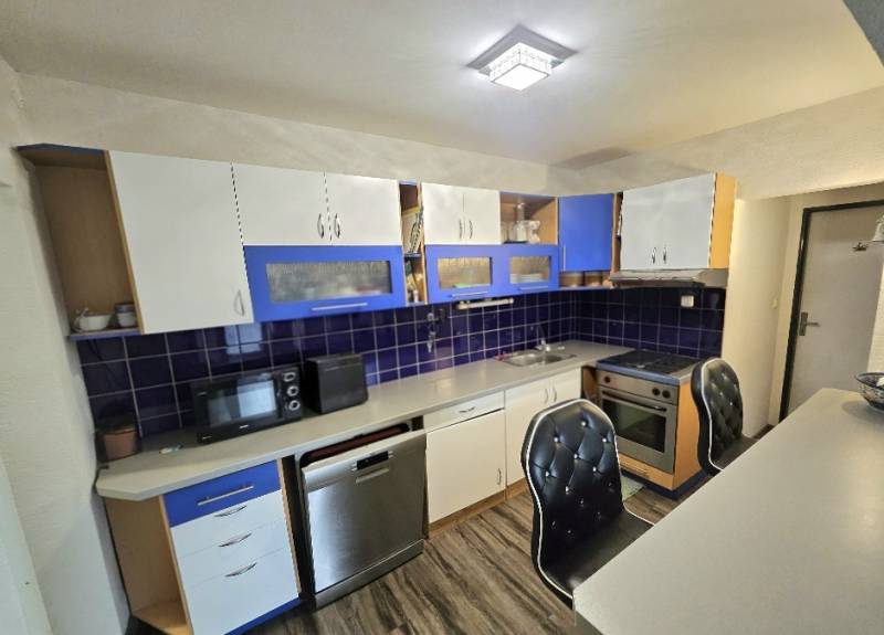 Kuchyně v 3-pokojovém bytě s podlahou s dřevěným dekorem a modrými detaily.