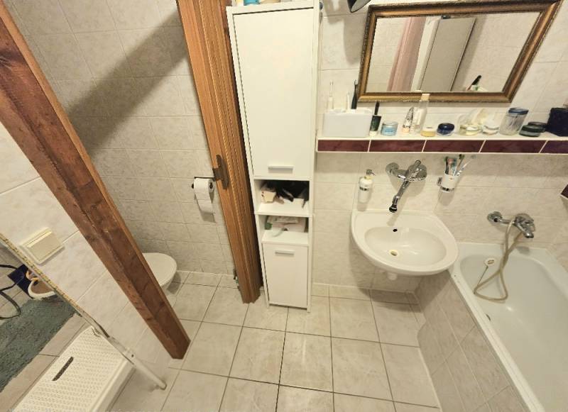 Koupelna v 3-pokojovém bytě s vanou, umyvadlem a úložným prostorem.