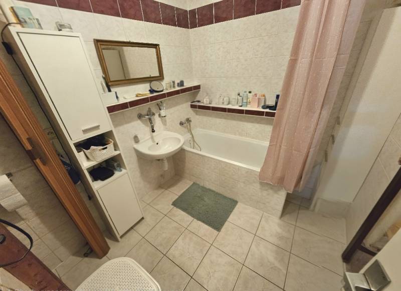 Koupelna v 3-pokojovém bytě s vanou, umyvadlem a úložným prostorem.