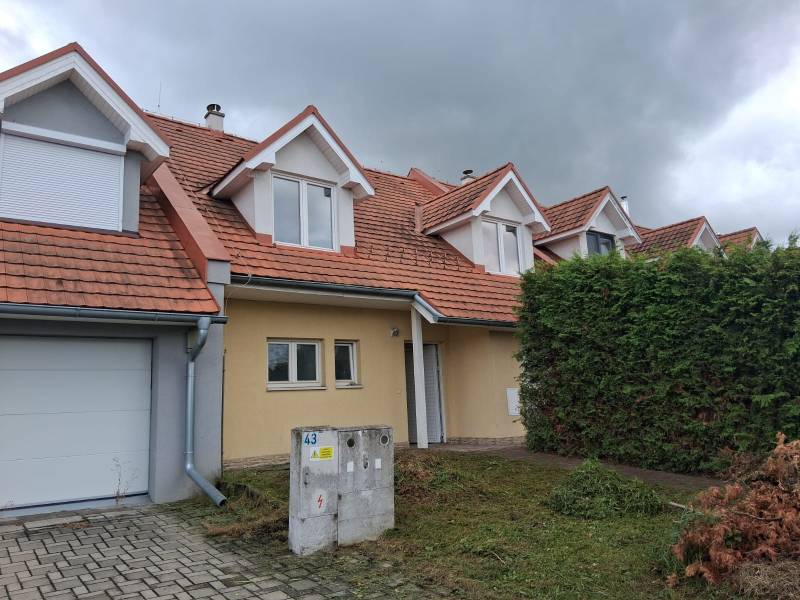 Rodinný dům v Ľubeli s červenou střechou, garáží a udržovanou zahradou.