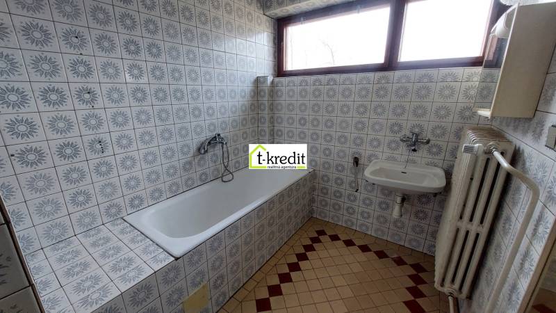 Koupelna s obklady se vzorem, vanou, umyvadlem a radiátorem v rodinném domě.