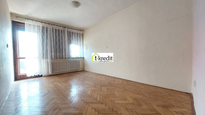 Pokoj v rodinném domě s podlahou s dřevěným dekorem a velkým oknem.