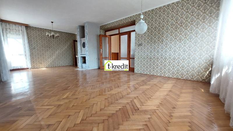 Prostorný pokoj s podlahou s dřevěným dekorem a vzorovanými tapetami v rodinném domě.