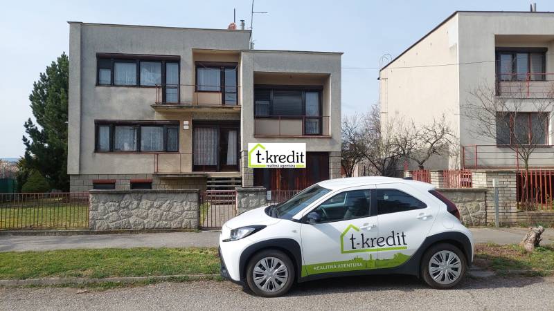 Rodinný dům ve Zlatých Moravcích se zaparkovaným autem realitní kanceláře před domem.