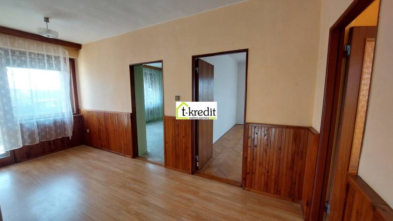 Pokoj v rodinném domě s podlahou s dřevěným dekorem a dřevěným obkladem stěn.