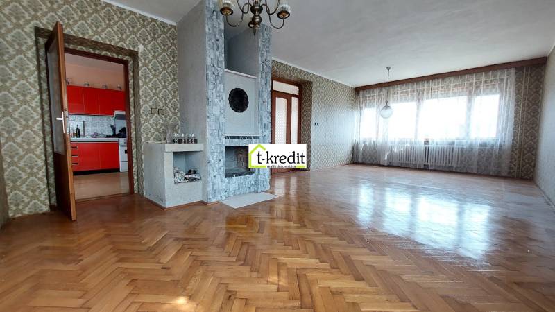 Obývací pokoj v rodinném domě s krbem a podlahou s dřevěným dekorem.