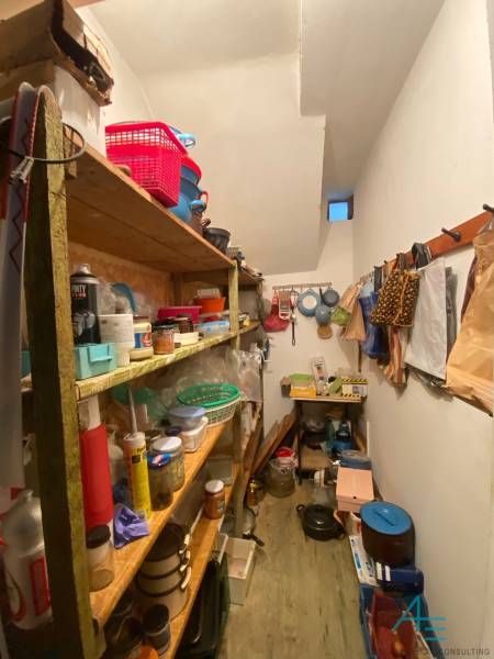 Úložný prostor v rodinném domě s policemi a různými kuchyňskými předměty.