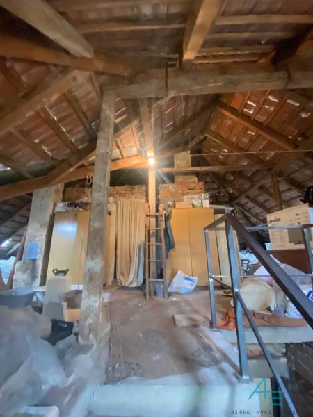 Podkroví rodinného domu s dřevěnými trámy, šikmou střechou a uskladněnými věcmi.