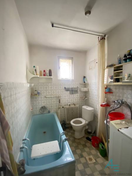 Koupelna v rodinném domě s vanou, pračkou a oknem.