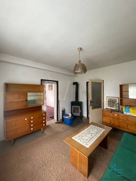 Obývací pokoj v rodinném domě s dřevěným nábytkem a kamny na topení.