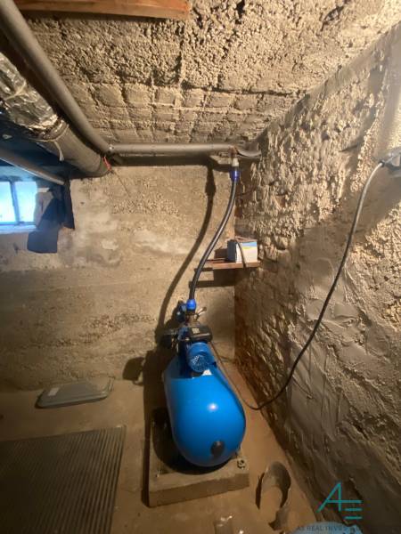 Sklep rodinného domu s čerpadlem a jednoduchými betonovými stěnami.