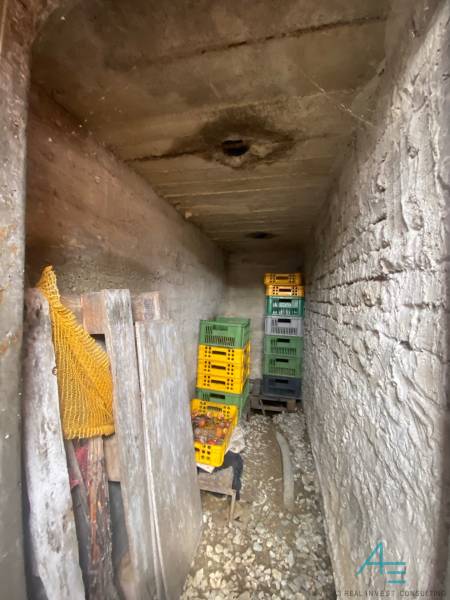 Úzký kamenný sklad v rodinném domě s plastovými přepravkami na zeleninu.