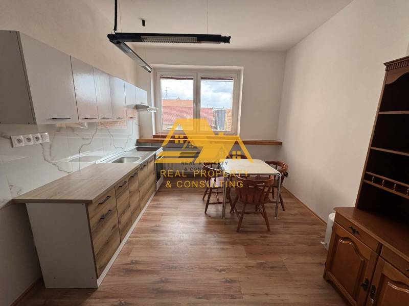 Kuchyně v 1-pokojovém bytě se stolem, židlemi a podlahou s dřevěným dekorem.