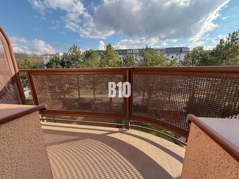 Výhled z balkonu v Rekreačním apartmánu na Halalovce v Trenčíně, obklopený stromy.