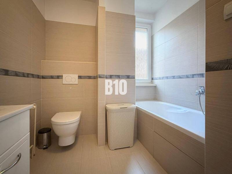 Koupelna v rekreačním apartmánu s vanou, toaletou a moderními obklady.