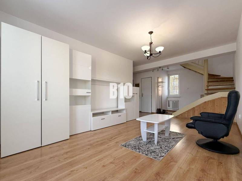 Obývací pokoj v rekreačním apartmánu s bílým nábytkem a podlahou s dřevěným dekorem.