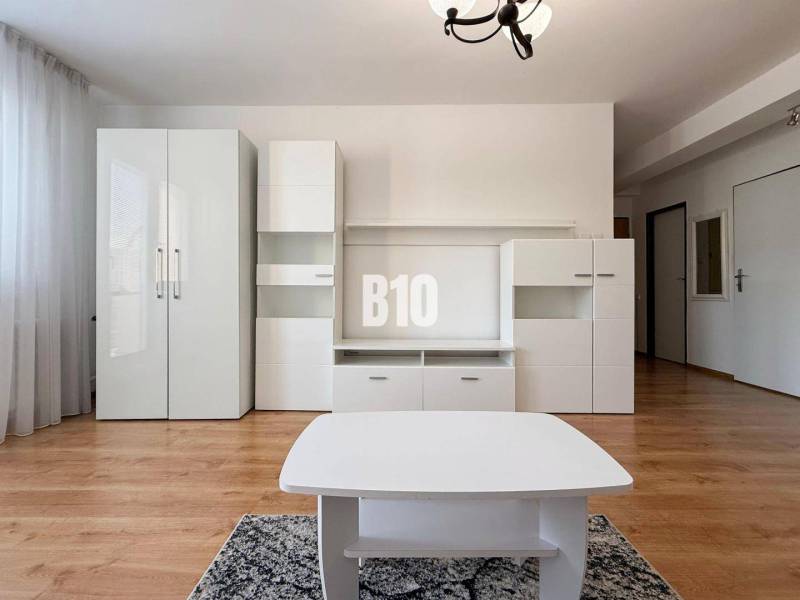 Interiér rekreačního apartmánu s bílým nábytkem a podlahou s dřevěným dekorem.