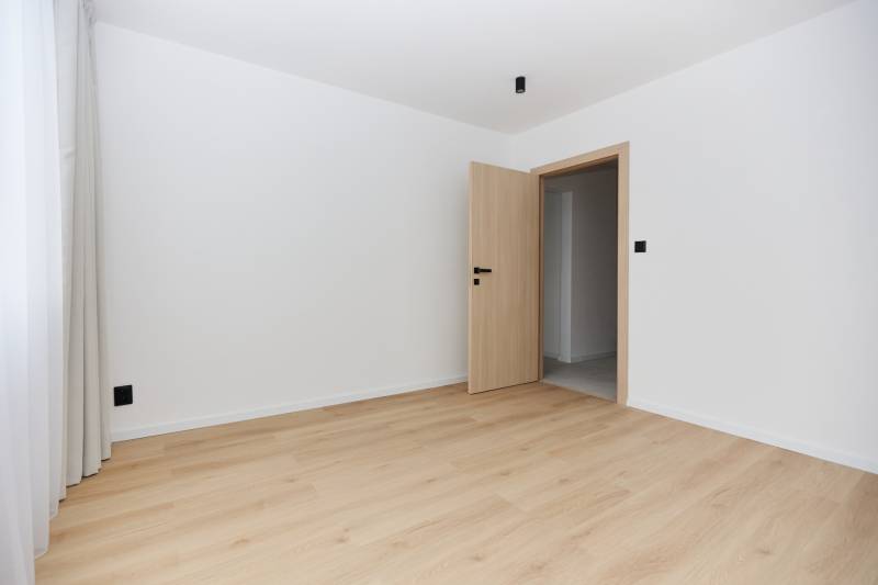 Pokoj s podlahou s dřevěným dekorem a dveřmi v 3-pokojovém bytě.