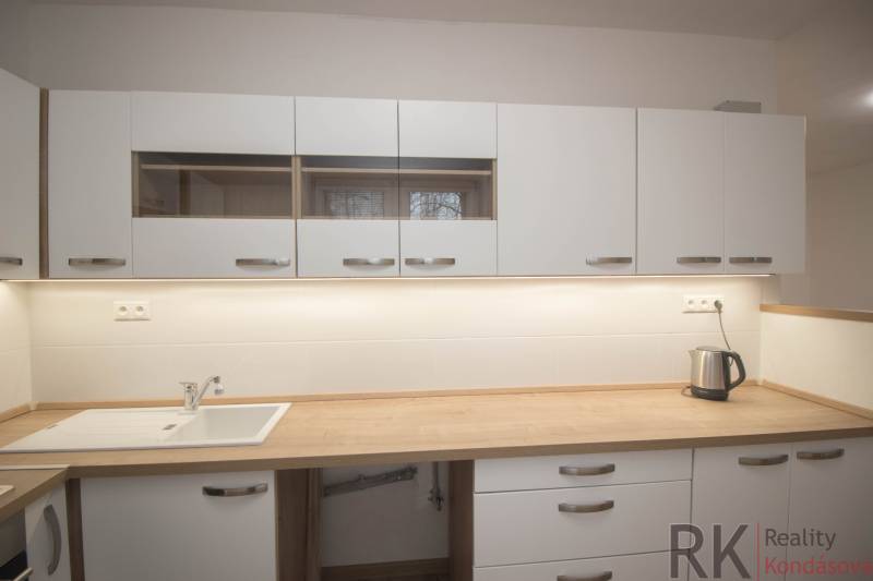 Kuchyňská linka v 2-pokojovém bytě s dřevěným dekorem pracovní desky.