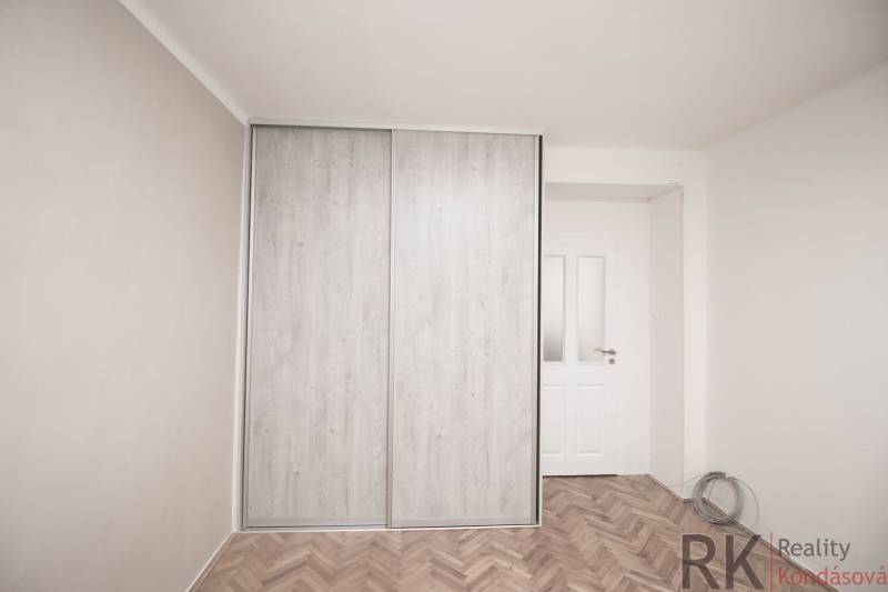 Šatník s posuvnými dveřmi v 2-pokojovém bytě, podlaha s dřevěným dekorem.
