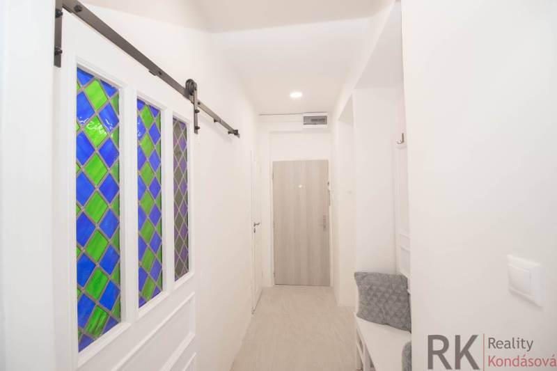 Chodba s vitrážovými dveřmi, věšáky a dřevěným dekorem v 2pokojovém bytě.