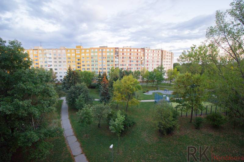 Velký bytový dům obklopený stromy a udržovanými chodníky na Krakovské v Košicích.