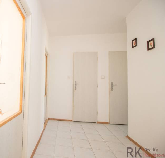 Chodba se světlými stěnami a bílými dveřmi ve 4-pokojovém bytě.