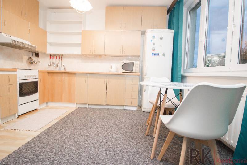 Kuchyně s bílým nábytkem a jídelním stolem ve 4-pokojovém bytě.