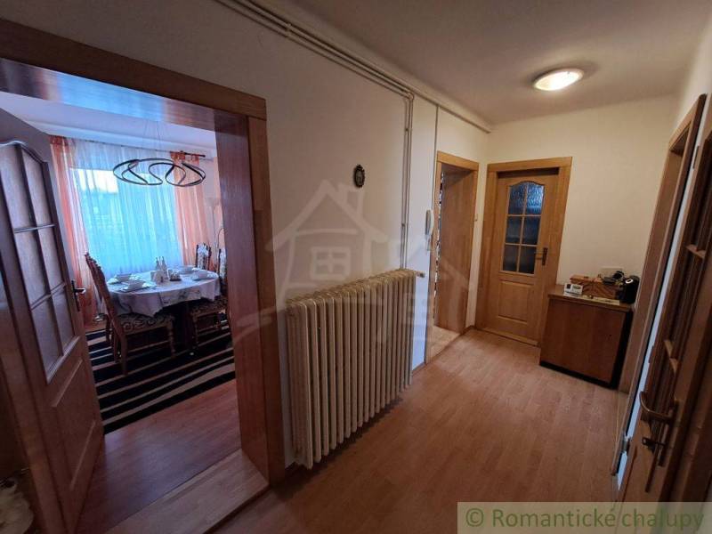 Chodba s podlahou s dřevěným dekorem v rodinném domě, útulné uspořádání nábytku.