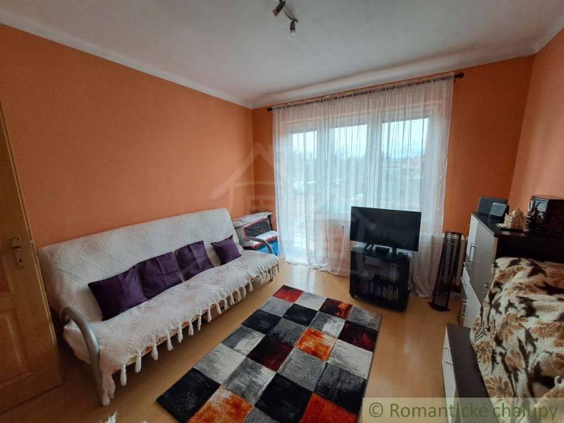 Obývací pokoj v rodinném domě s podlahou s dřevěným dekorem a oranžovými stěnami.