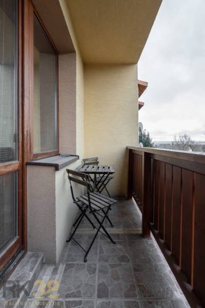 Balkon s dřevěným zábradlím a stolem se dvěma židlemi v bytě s 5 a více pokoji.