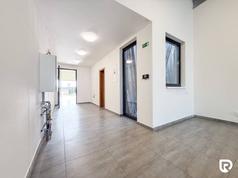 Interiér obchodního prostoru s dlážděnou podlahou a prosklenými dveřmi.