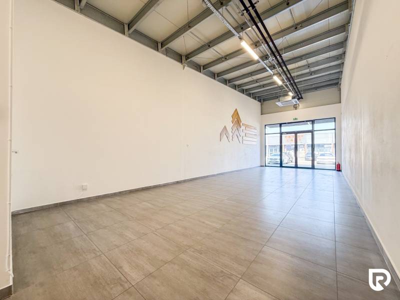 Interiér obchodních prostor s velkoformátovými okny a světlou podlahou.