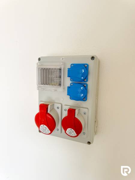 Elektroinstalační panel s průmyslovými zásuvkami v obchodních prostorách.