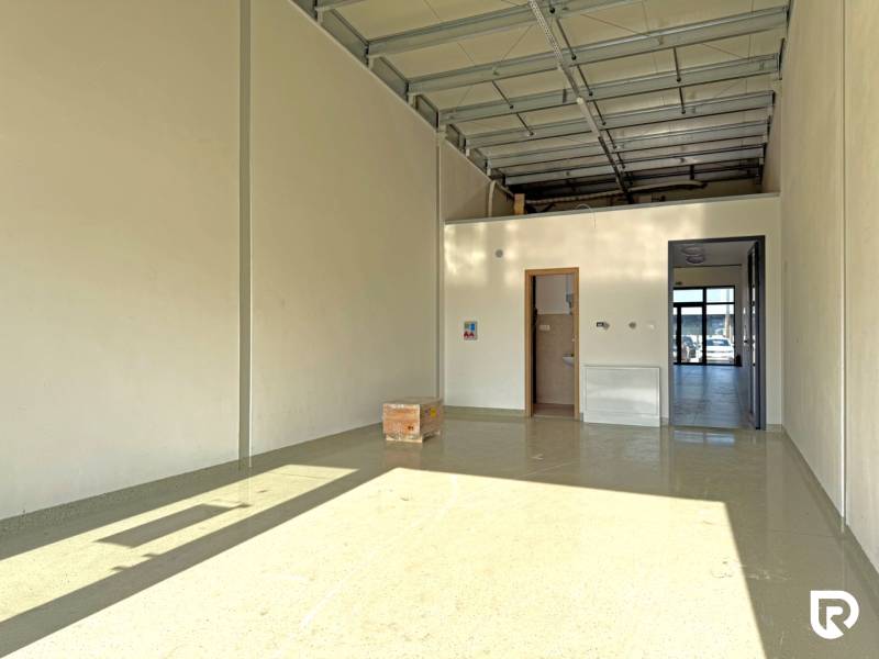 Prostorné obchodní prostory s vysokým stropem a betonovou podlahou.