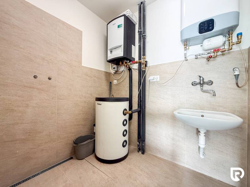 Interiér obchodních prostor s vytápěcím systémem, umyvadlem a podlahou s dřevěným dekorem.