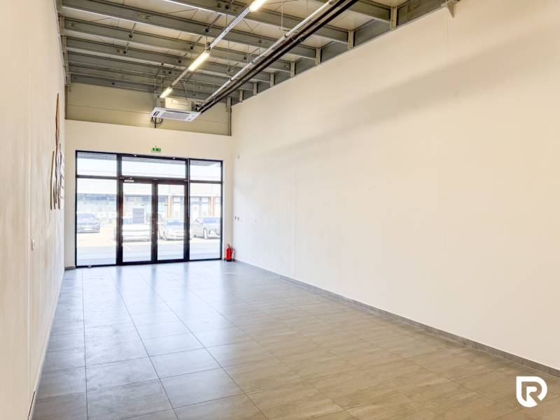 Prostorné obchodní prostory s dlažbou a velkými dveřmi.