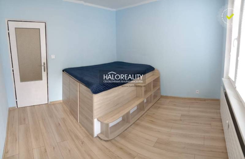 Ložnice s vyvýšeným lůžkem a podlahou s dřevěným dekorem v 3-pokojovém bytě.