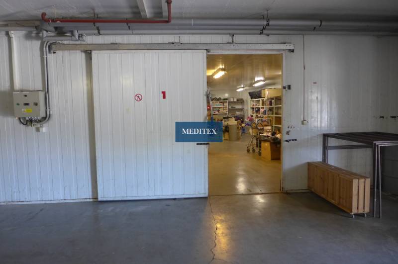 Otevřená hala se skladovaným materiálem, regály a průmyslovými dveřmi, Sklady a haly.