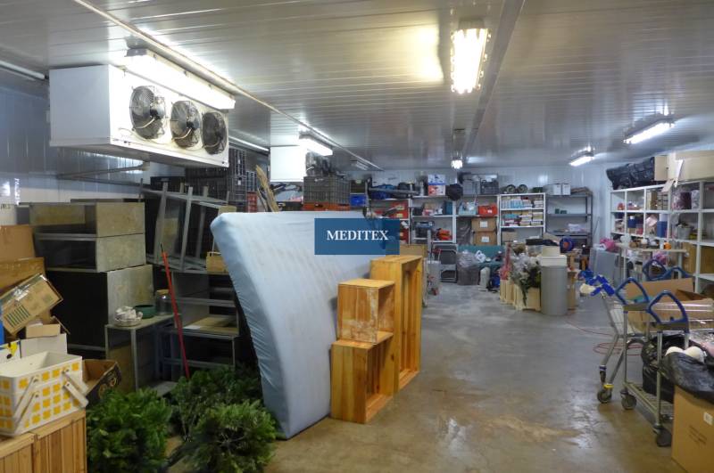 Sklady a haly s různým inventářem a úložnými regály.