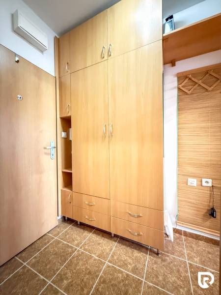 V garsonce je vestavěná skříň s dřevěným dekorem a dlažbou na podlaze.